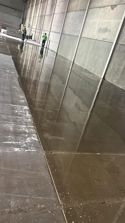 Avance de la primera capa sobre el piso de concreto a lo largo del muro de una nave.