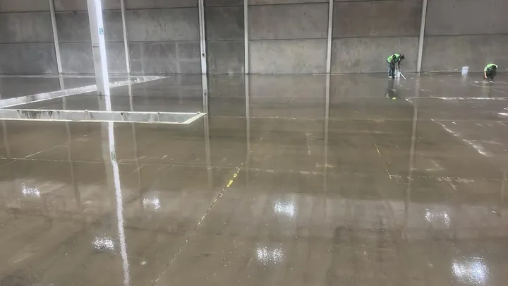 Primera capa recién aplicada sobre el concreto de una nave industrial de gran tamaño.
