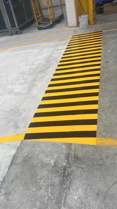 Franja de seguridad amarillo con negro delimitada por líneas de pasillo amarillas.