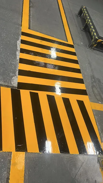 Zona de carga marcada con franjas amarillo y negro frente a una rampa niveladora.